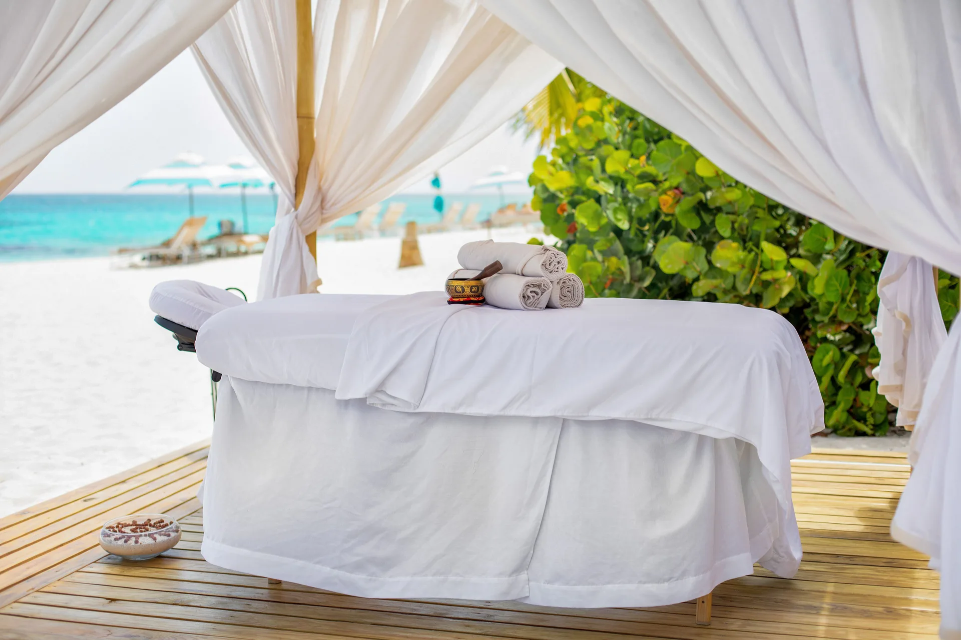 Massage table with towels under a white beach canopy at Zemi Beach House.