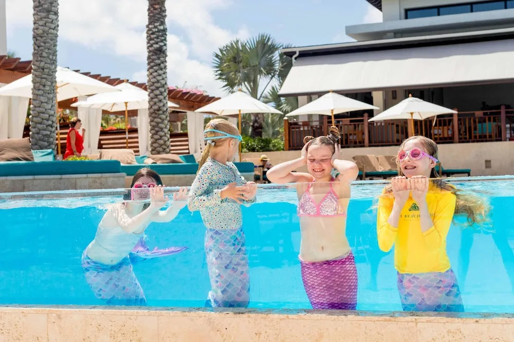 Children in mermaid tails posing in the pool at Zemi Beach House.