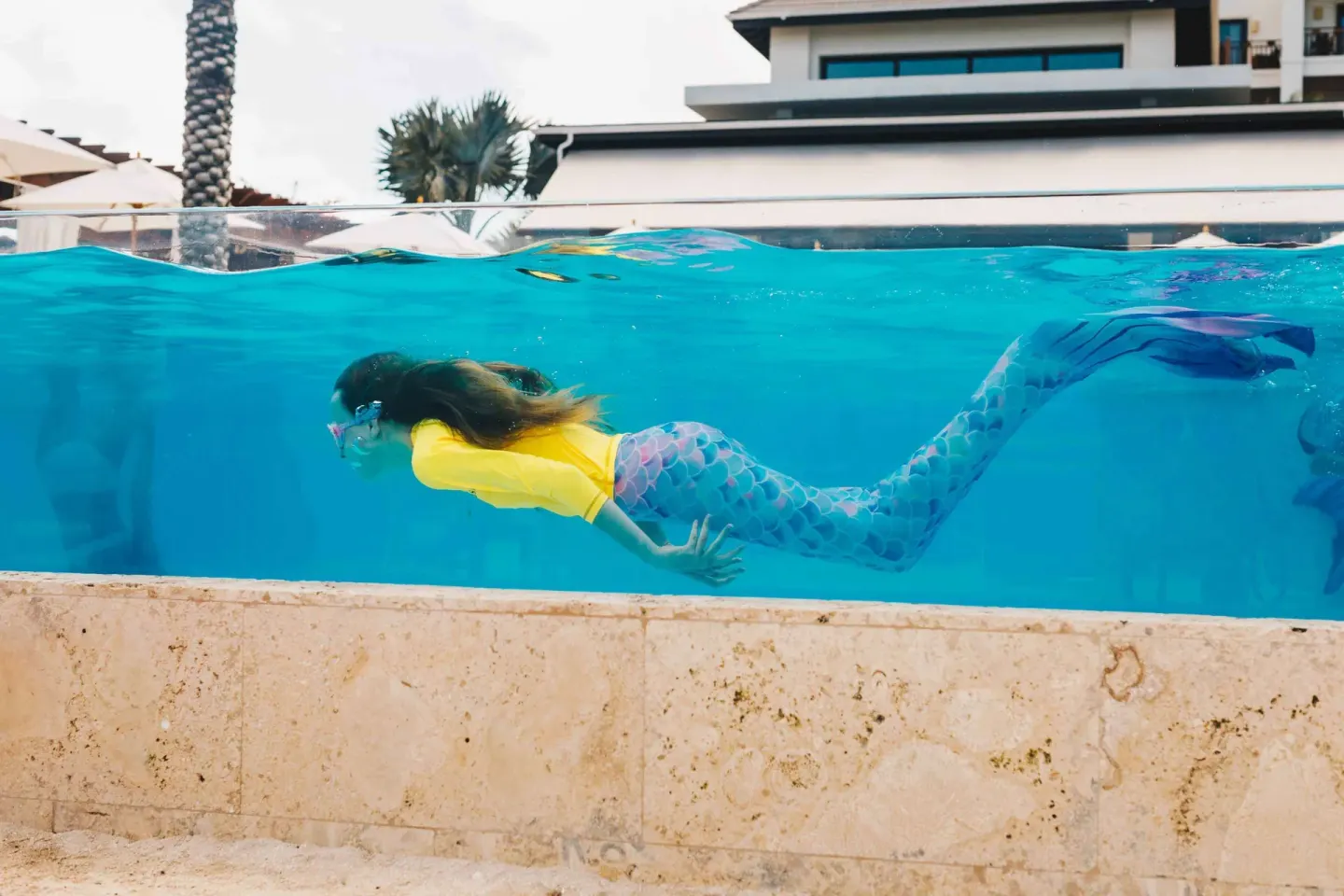 Child swimming underwater in a mermaid tail at Zemi Beach House.