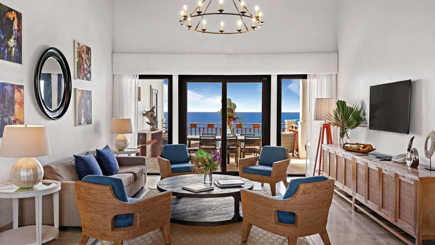 Ocean-view living room with blue chairs and balcony doors at Zemi Beach House.