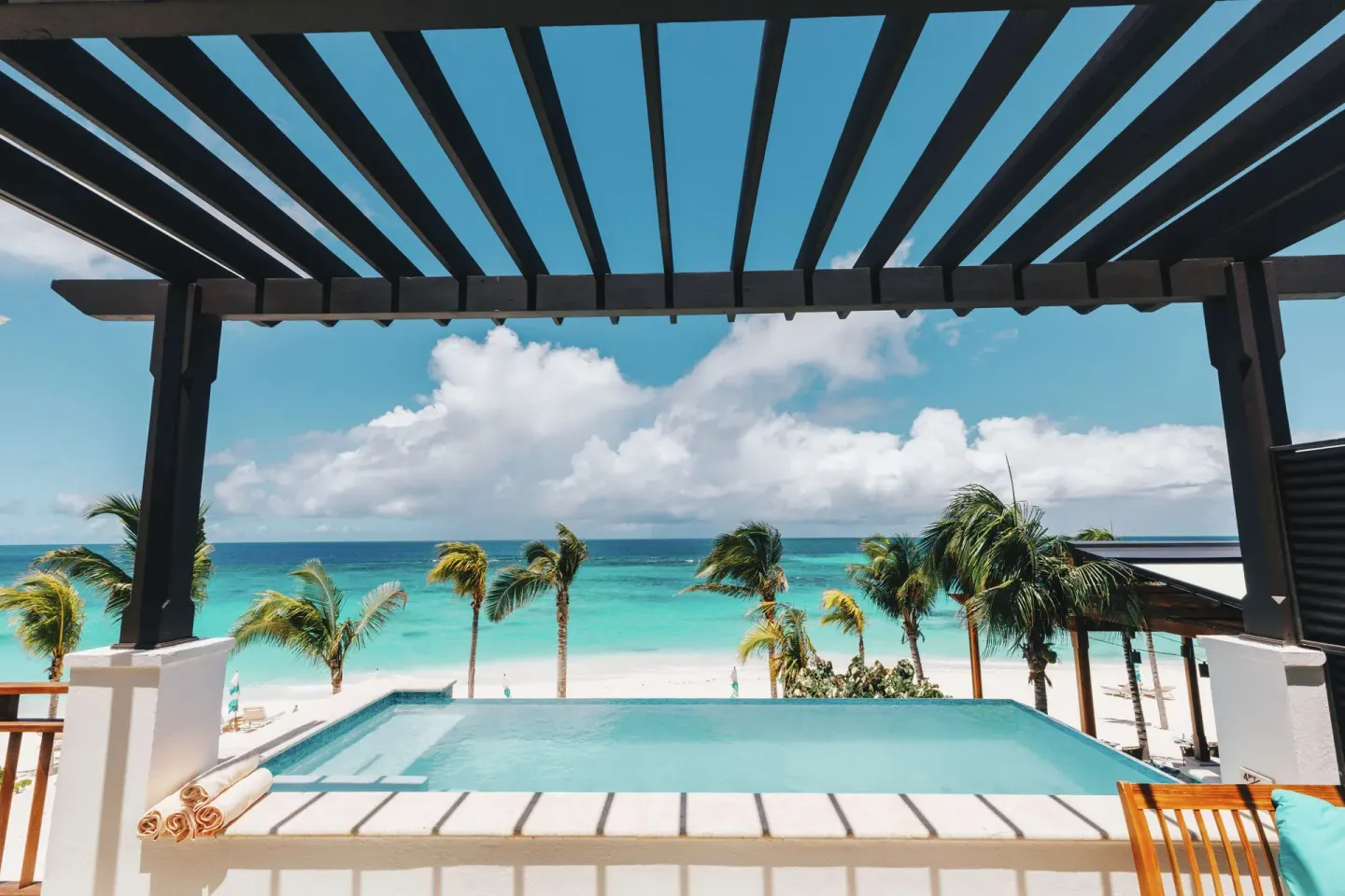 Pergola-framed infinity pool facing palms and beach at Zemi Beach House.
