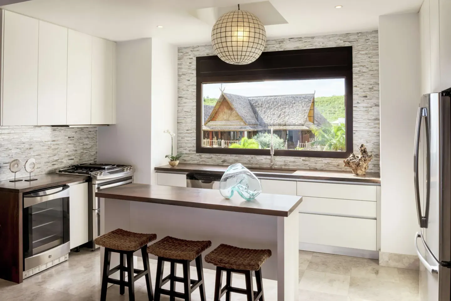 Bright resort kitchen with island seating and large window at Zemi Beach House.
