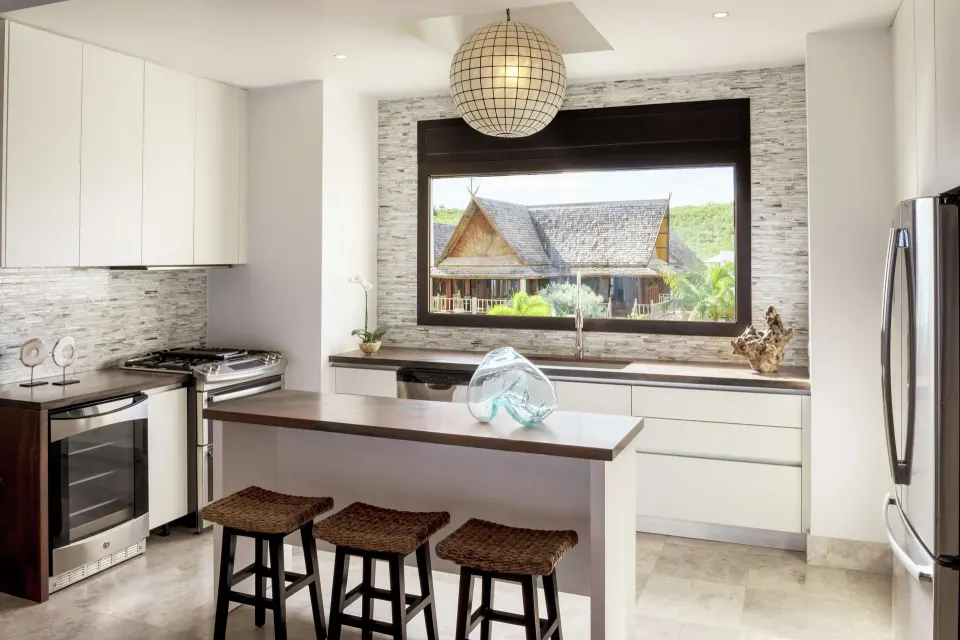 Bright resort kitchen with island seating and large window at Zemi Beach House.