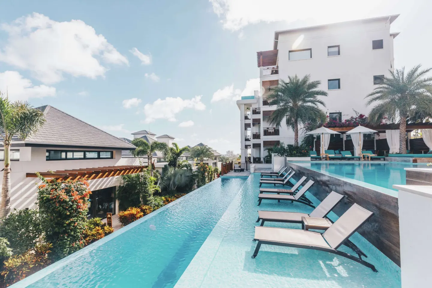 Resort pool with in-water loungers and guest buildings at Zemi Beach House.