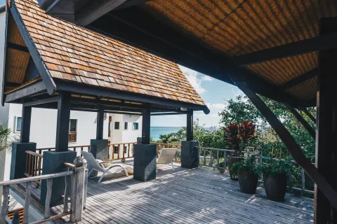 Wooden terrace with loungers and ocean glimpse at Zemi Beach House.