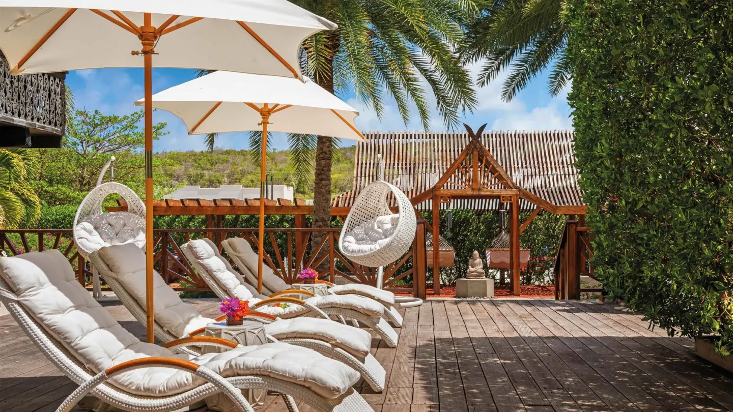 Spa deck with cushioned loungers, umbrellas, and hanging chairs at Zemi Beach House.