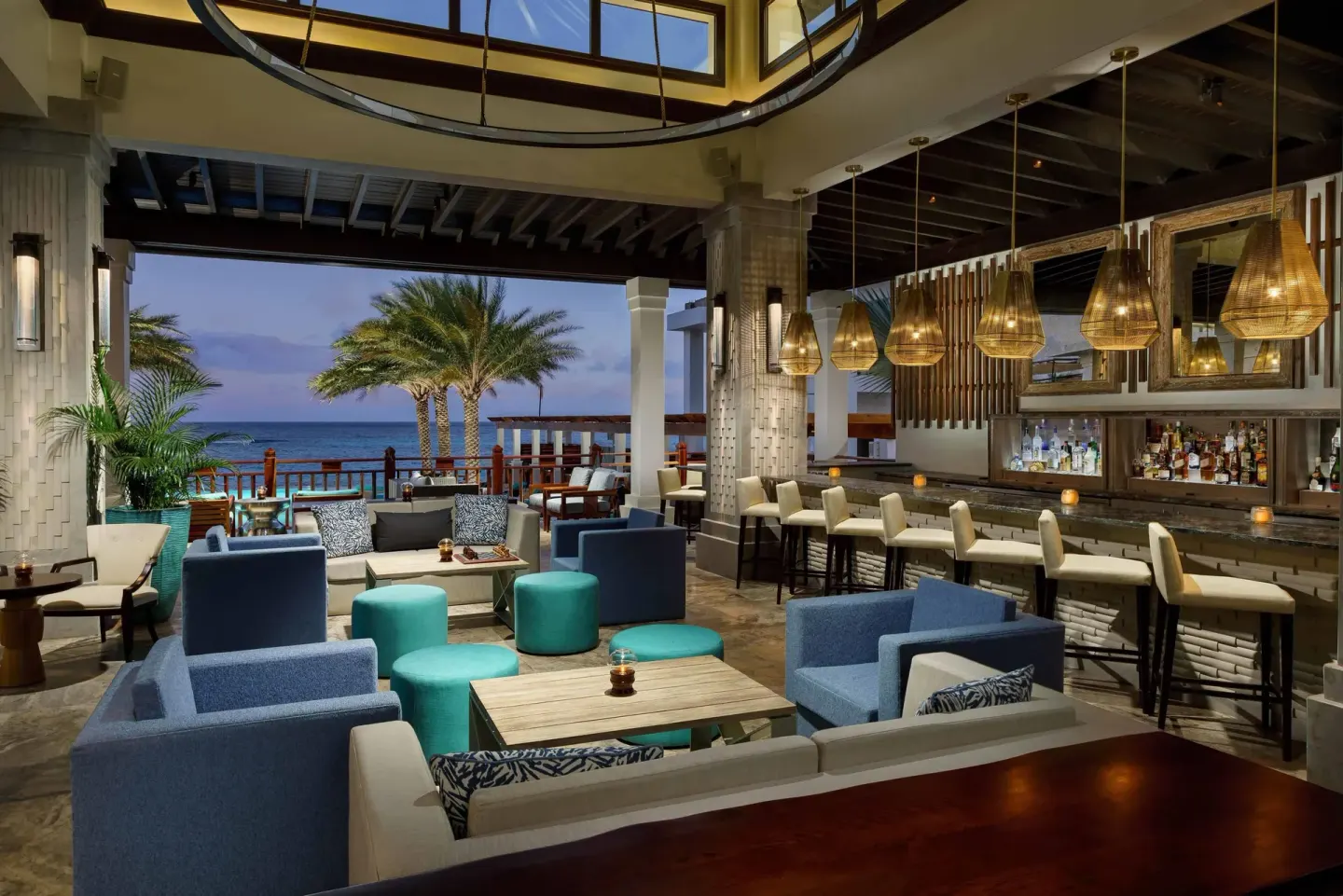 An open-air oceanfront bar lounge with blue seating at Zemi Beach House.