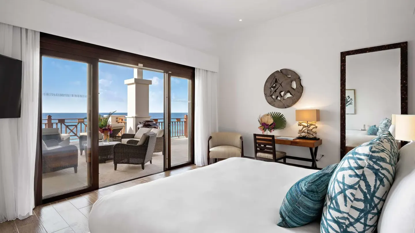 Oceanfront bedroom with bed, desk, and balcony seating at Zemi Beach House.