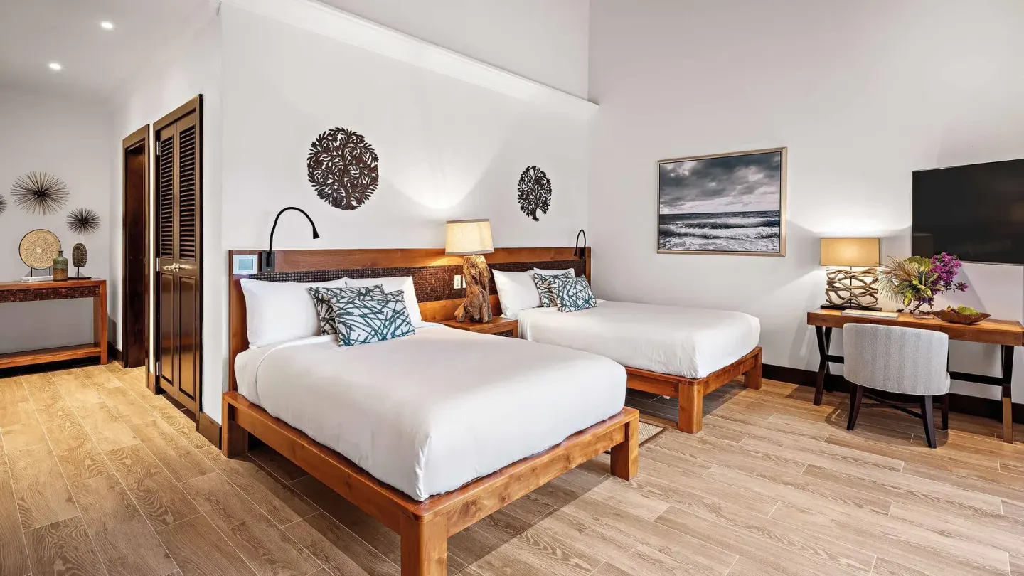 Second bedroom with two beds, desk, and wall art at Zemi Beach House.
