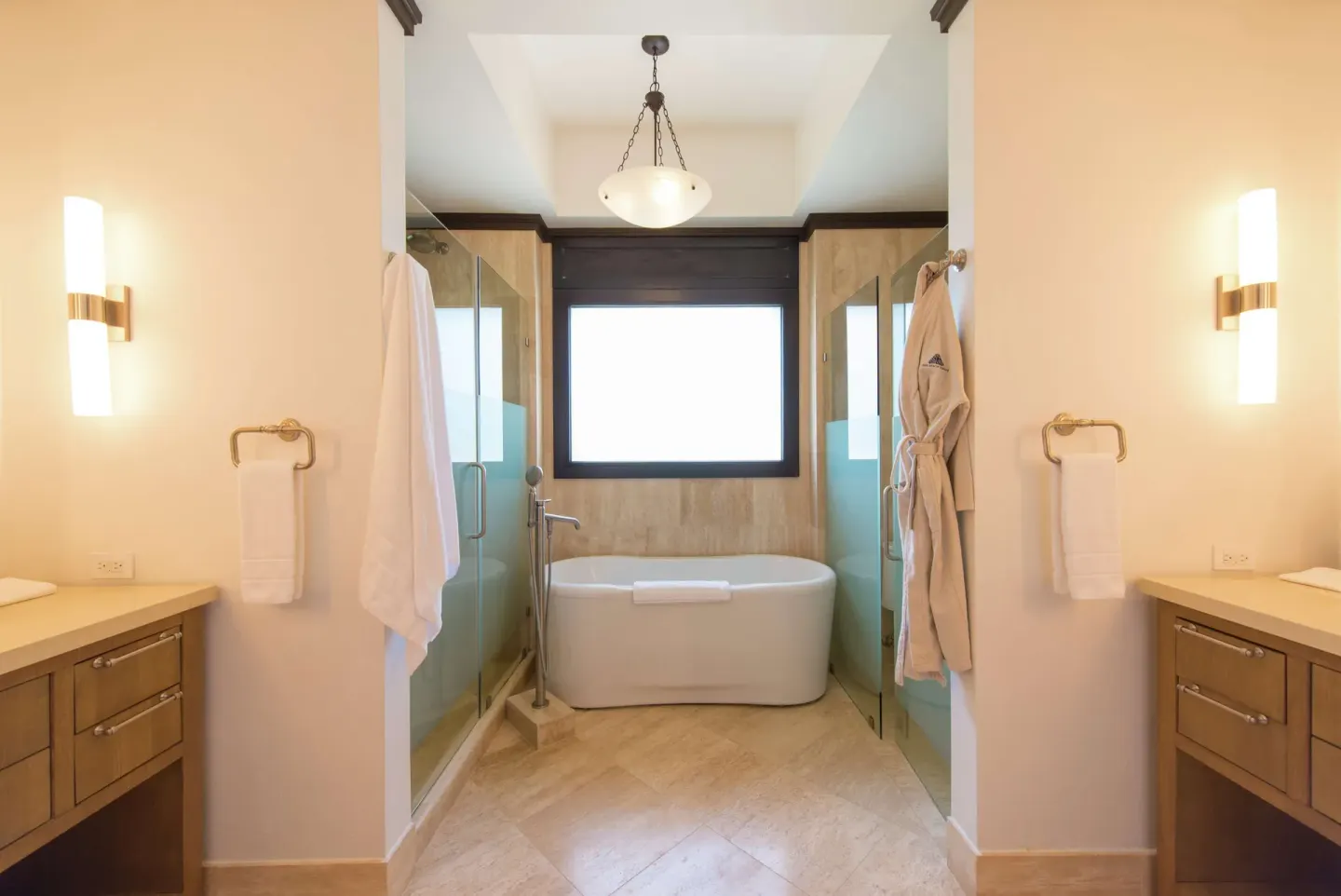 Ocean View room bathroom with soaking tub, glass showers, and vanities at Zemi Beach House.