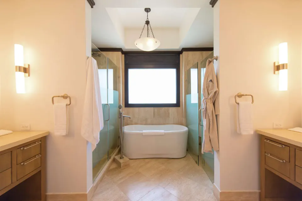 Ocean View room bathroom with soaking tub, glass showers, and vanities at Zemi Beach House.