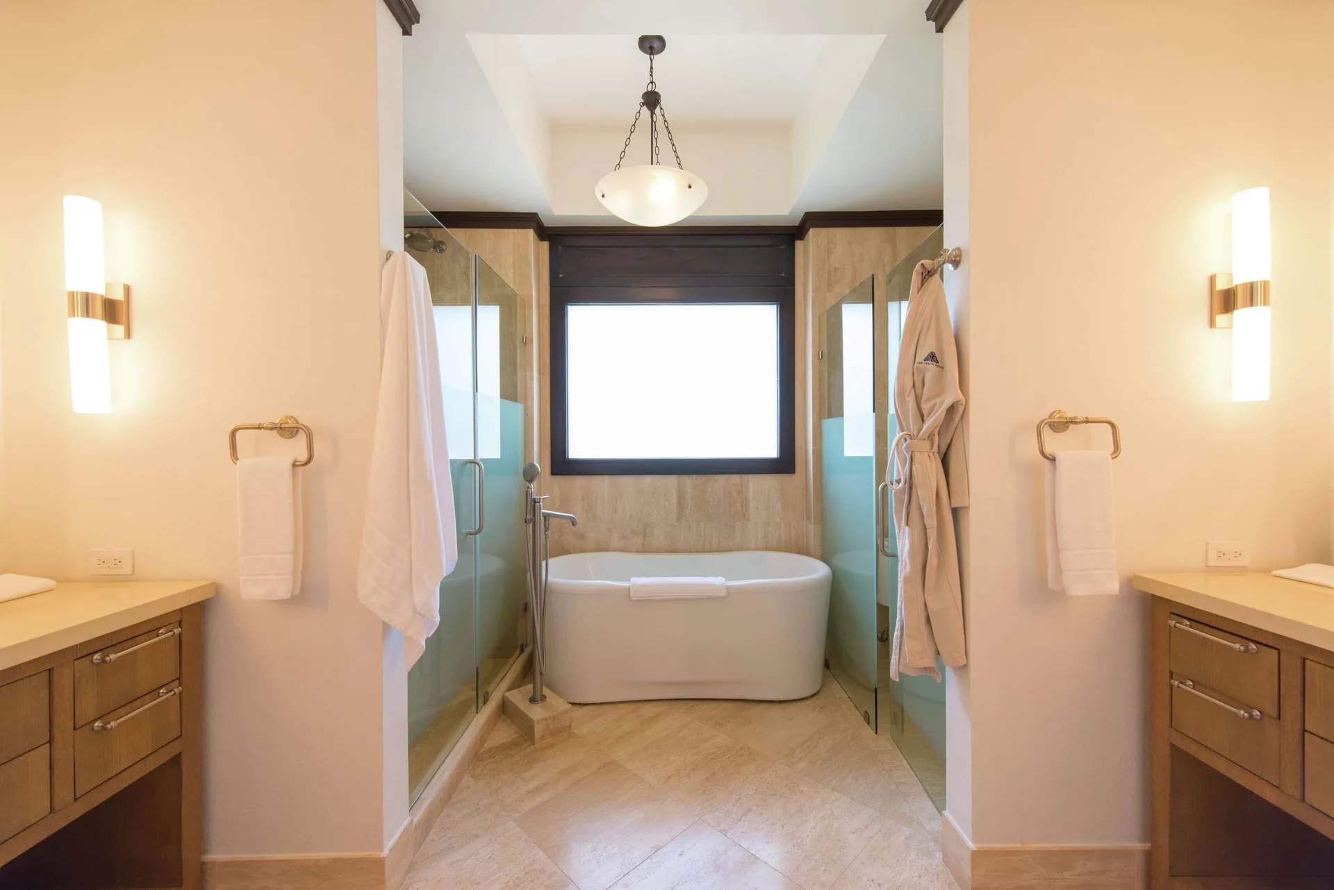 Ocean View room bathroom with soaking tub, glass showers, and vanities at Zemi Beach House.