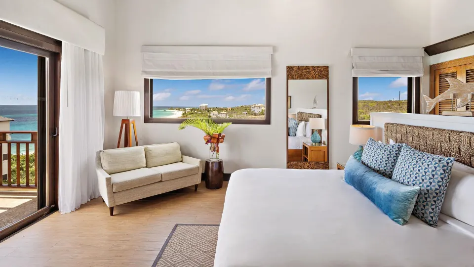 Ocean View room king bed, sofa, balcony door, and sea-facing windows at Zemi Beach House.